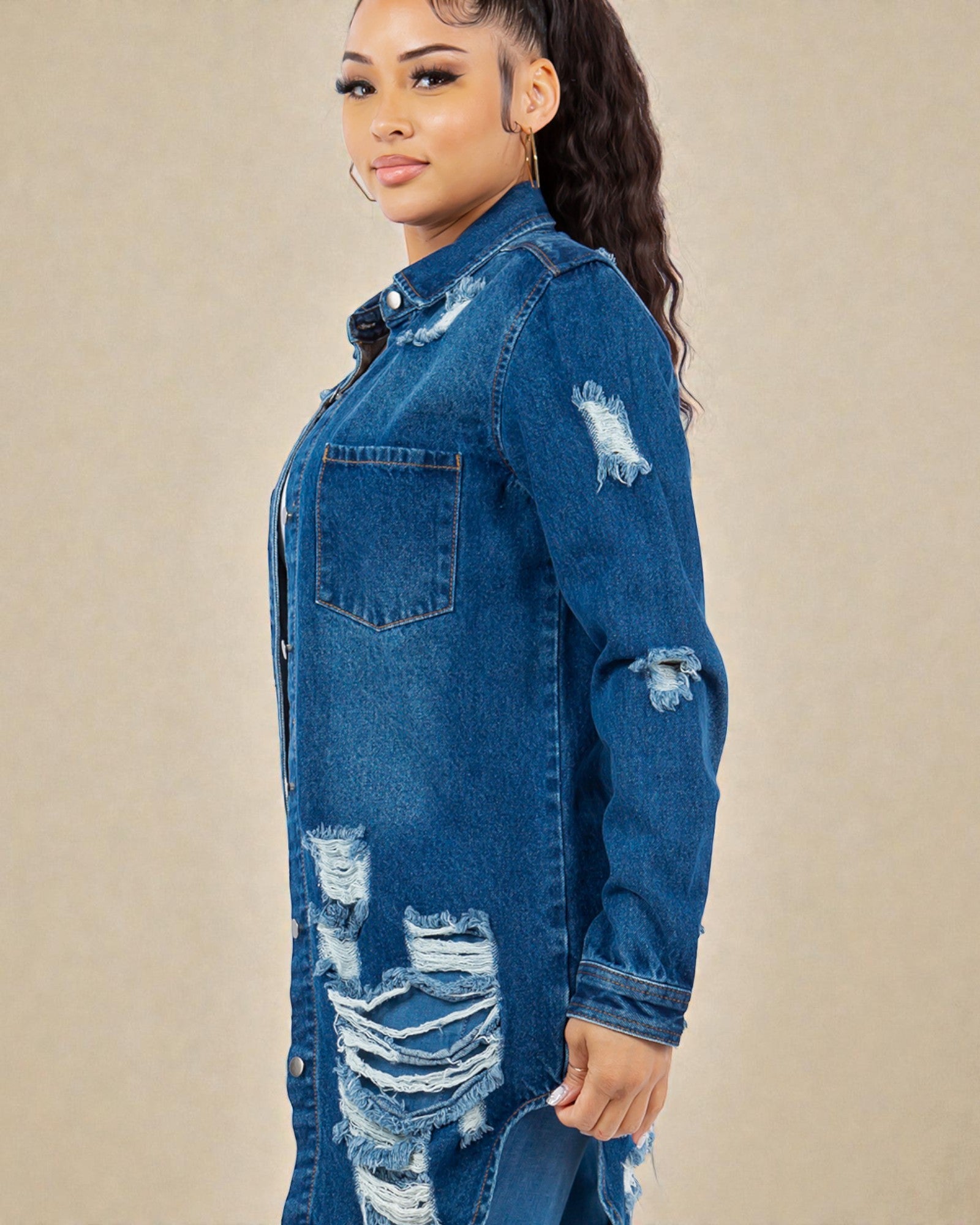 Woman wearing a blue denim jacket with distressed details on a beige background
