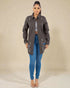 Woman wearing a gray jacket and blue jeans on a beige background