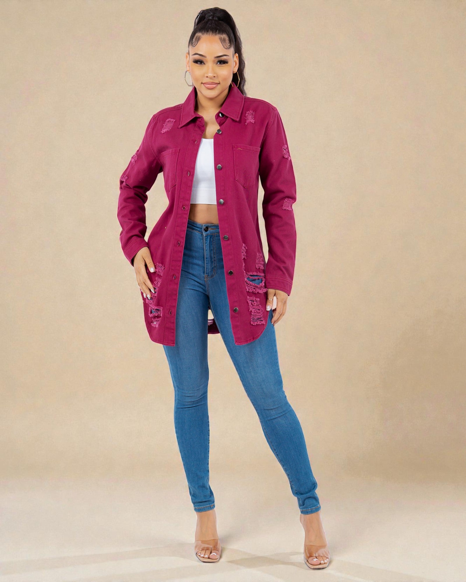 Woman wearing a magenta jacket and blue jeans on a beige background