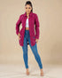 Woman wearing a magenta jacket and blue jeans on a beige background