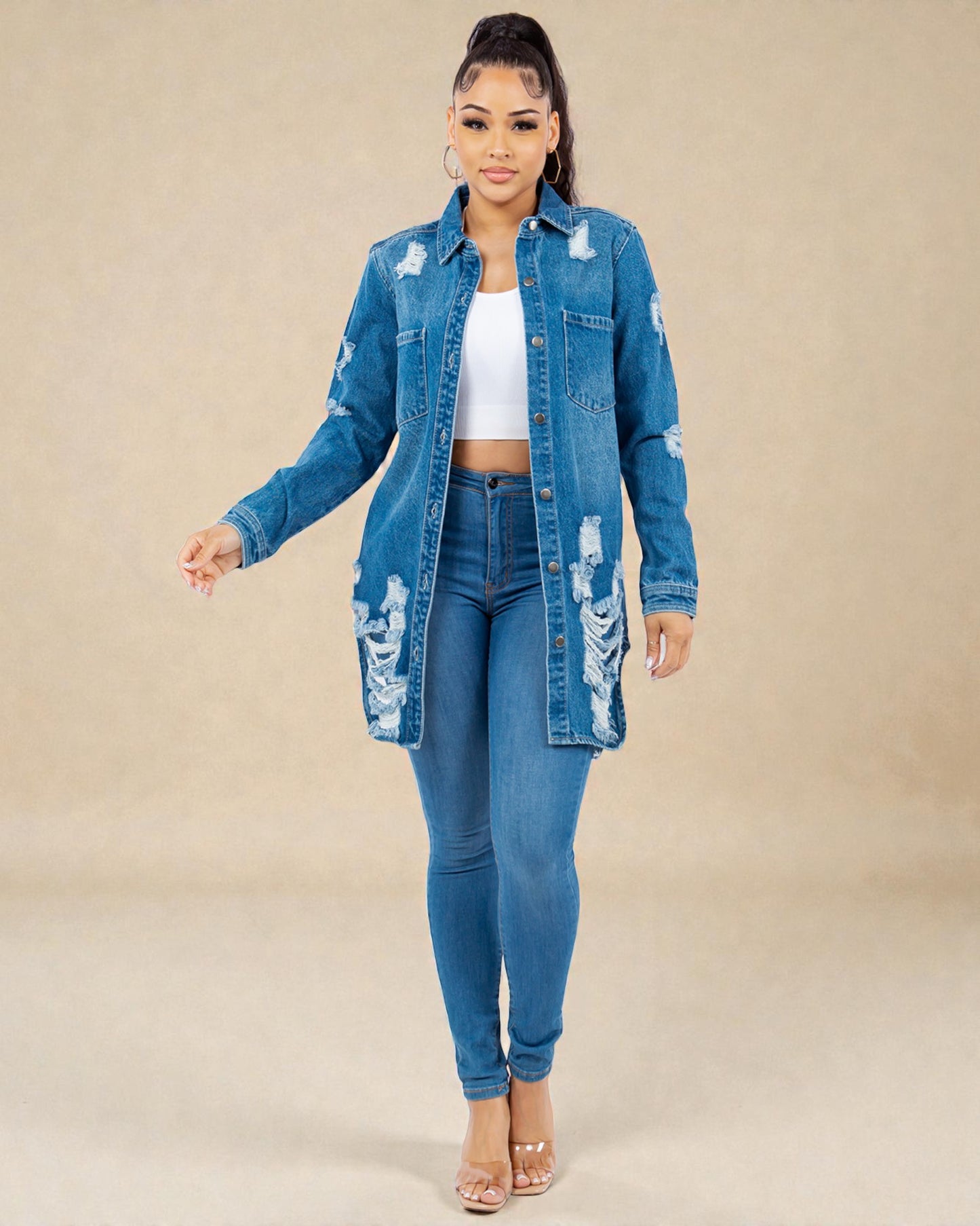 Woman wearing a distressed denim jacket and jeans on a beige background
