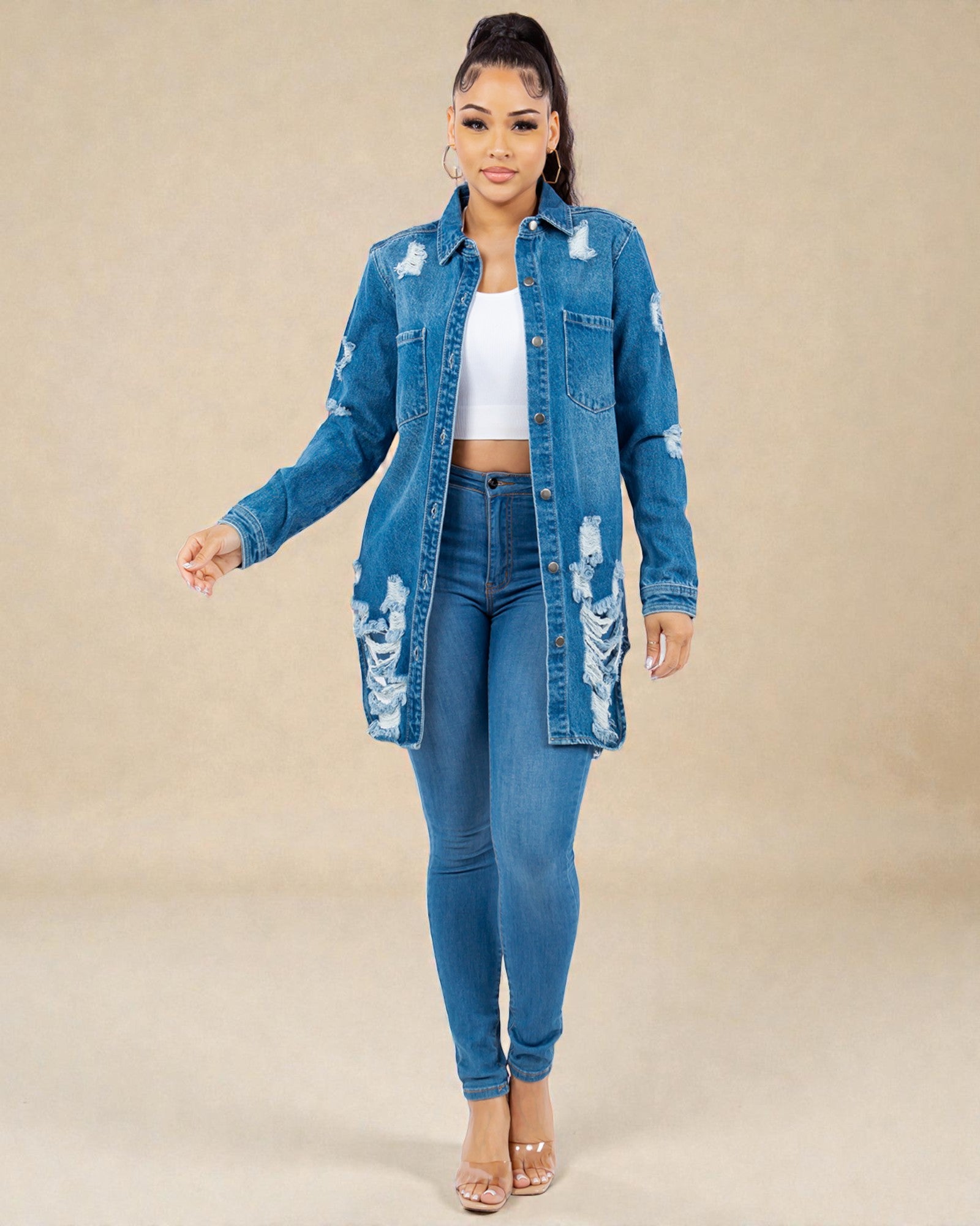 Woman wearing a distressed denim jacket and jeans on a beige background