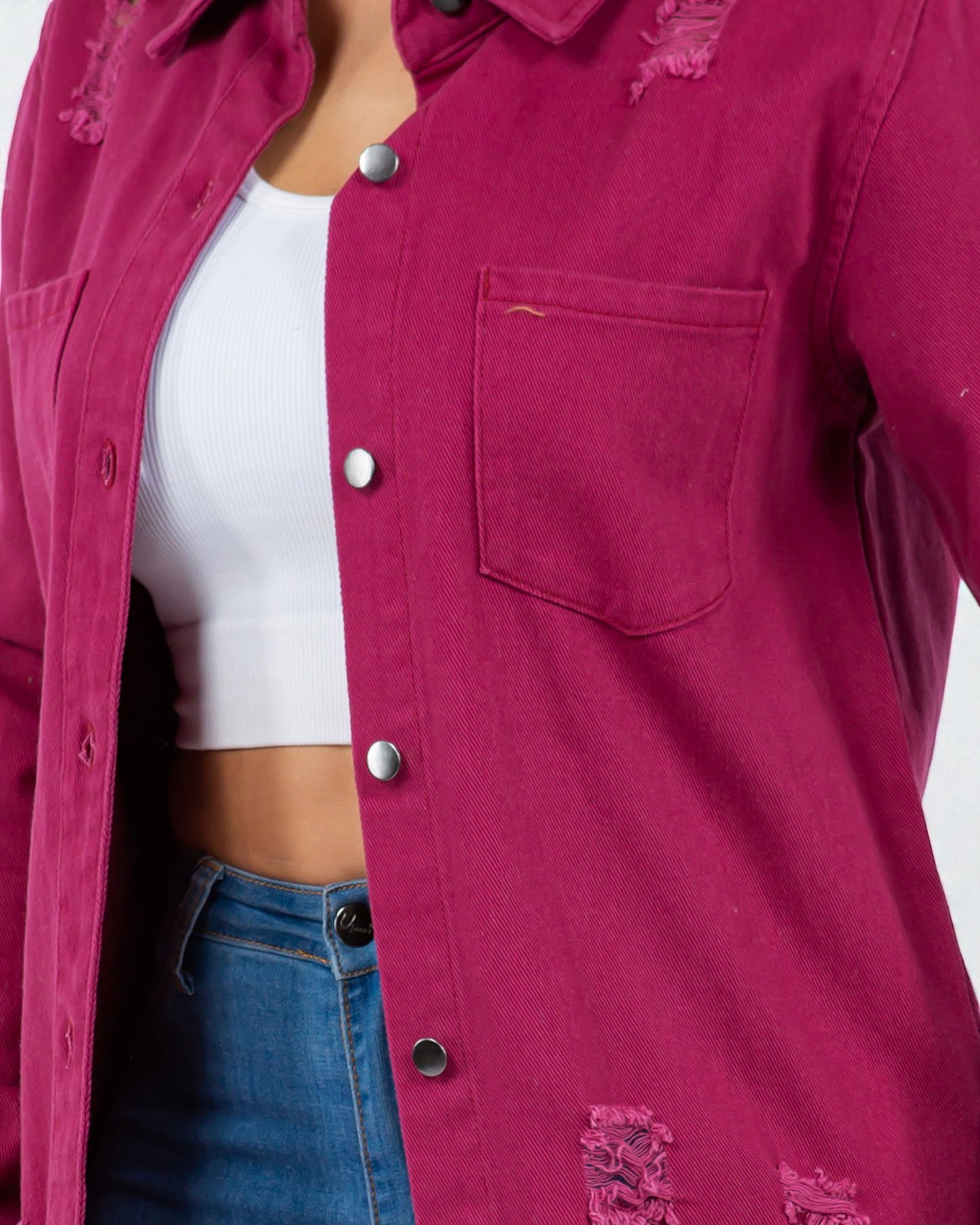 Close-up of a person wearing a pink shirt with a white crop top and blue jeans on a white background