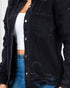 A close-up of a person wearing a dark washed distressed denim button-up shirt jacket over a white crop top and blue jeans.