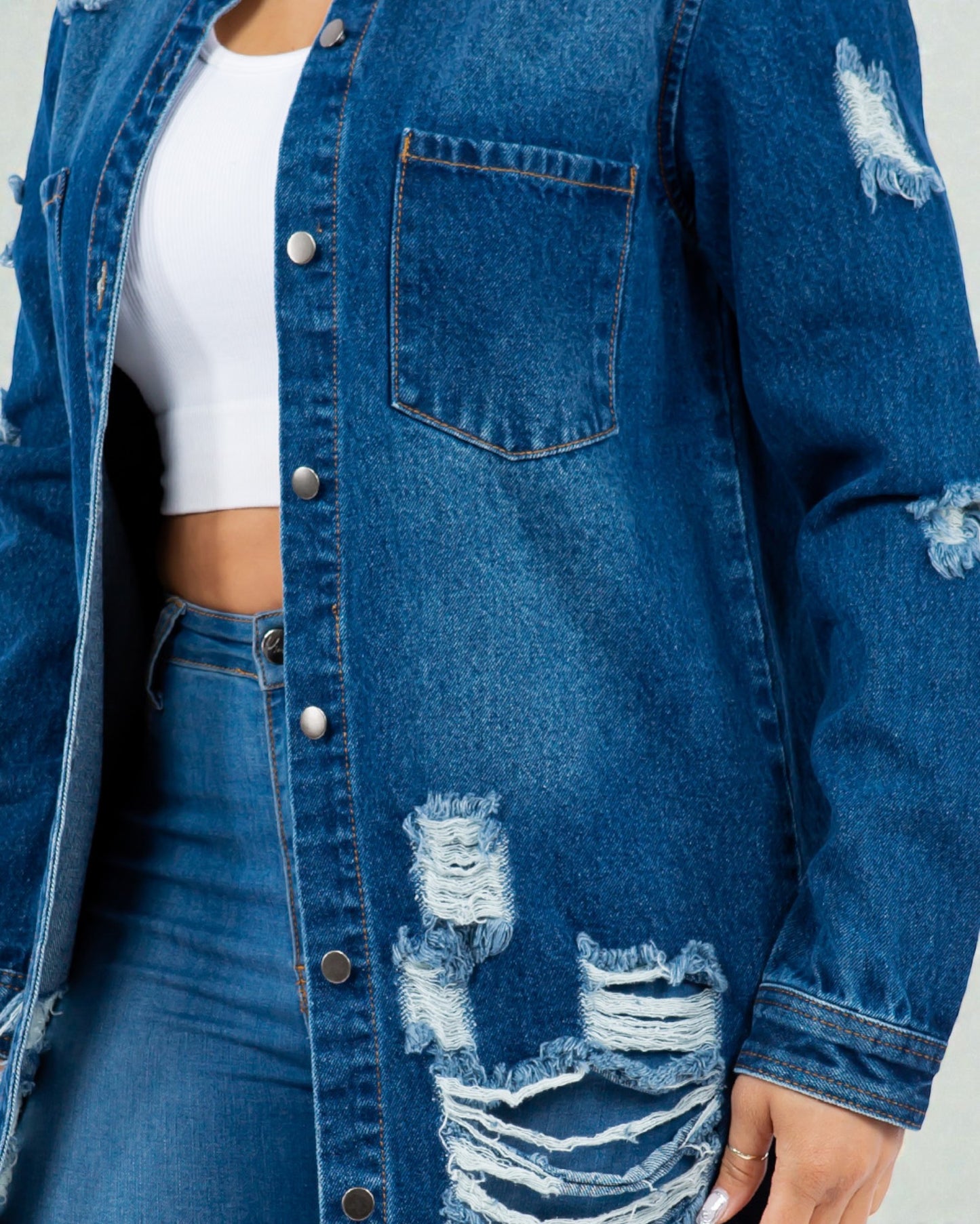 Blue denim jacket with distressed details on a plain background