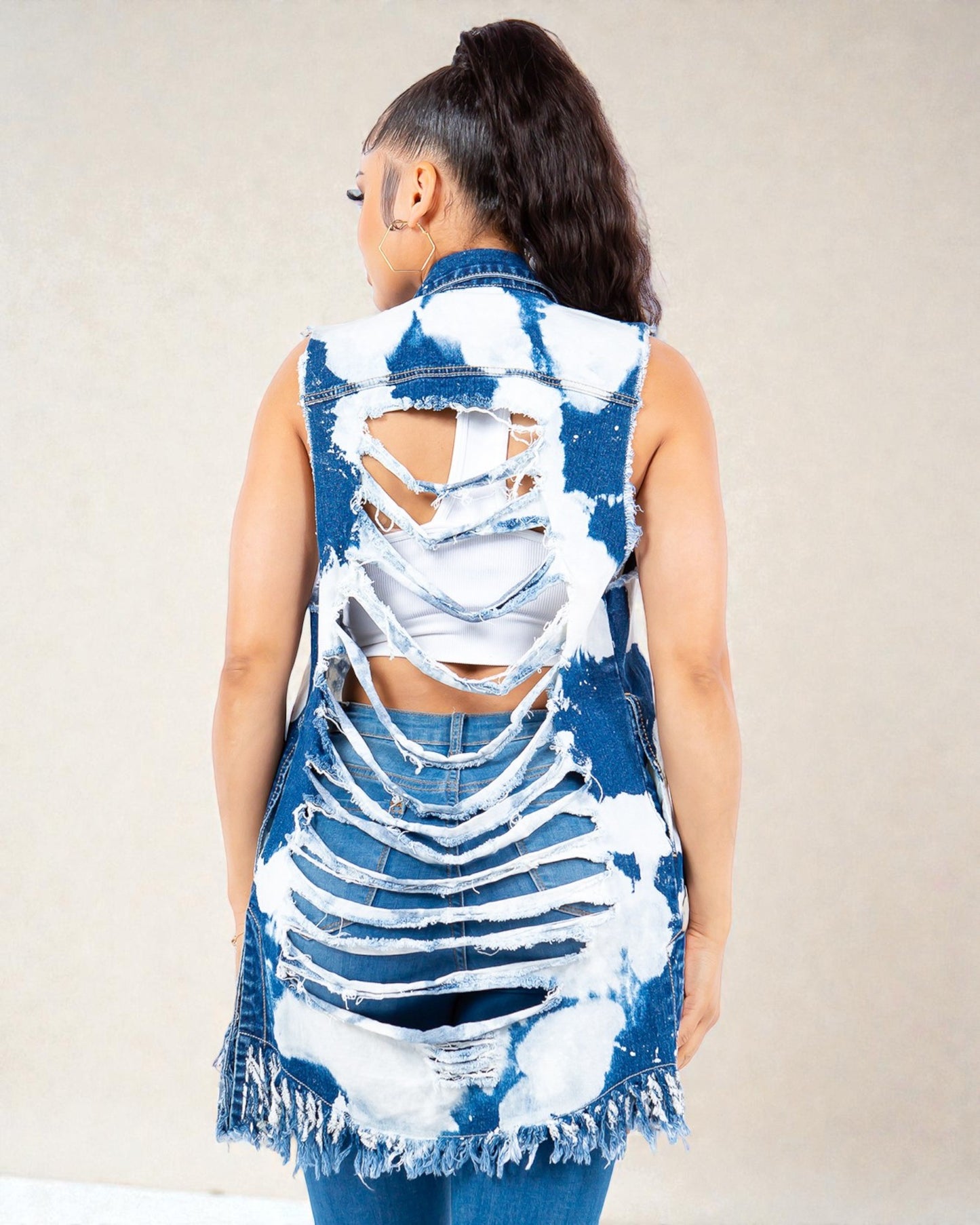 Person wearing a blue and white distressed denim vest on a plain background