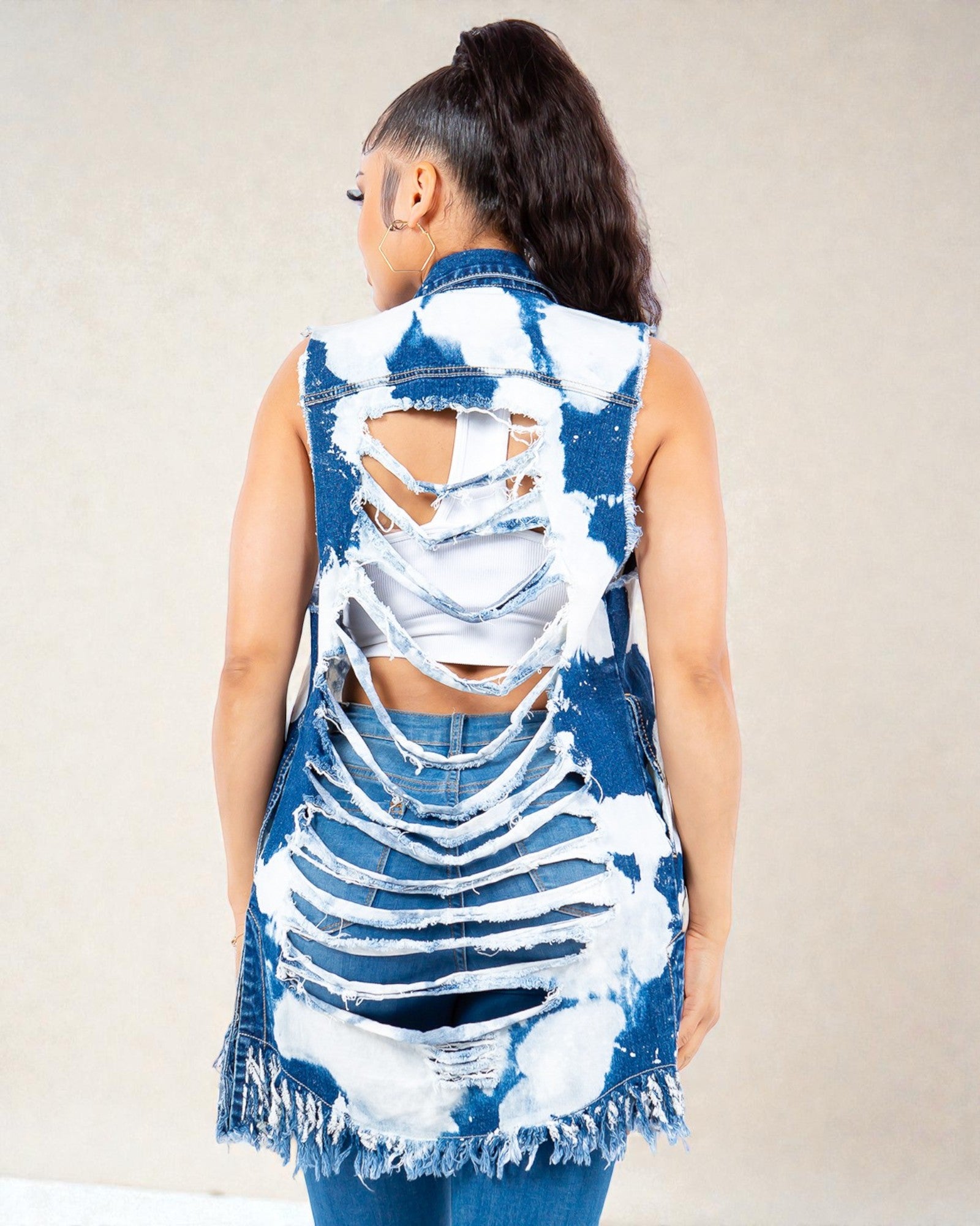 Person wearing a blue and white distressed denim vest on a plain background