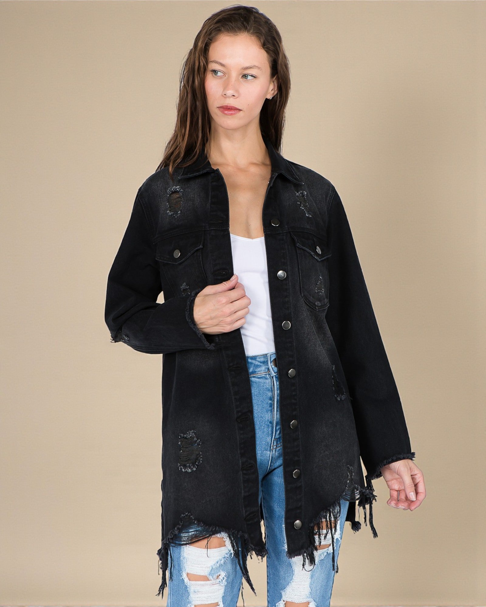 Woman wearing a black distressed denim jacket on a beige background