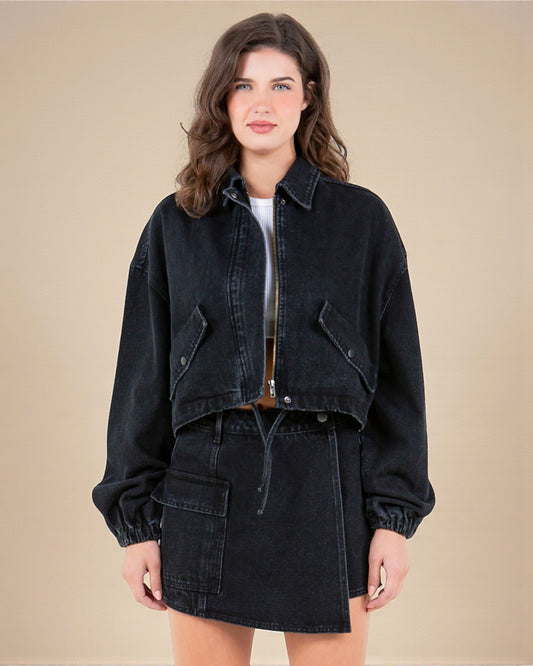 Woman wearing a black denim jacket and skirt on a beige background