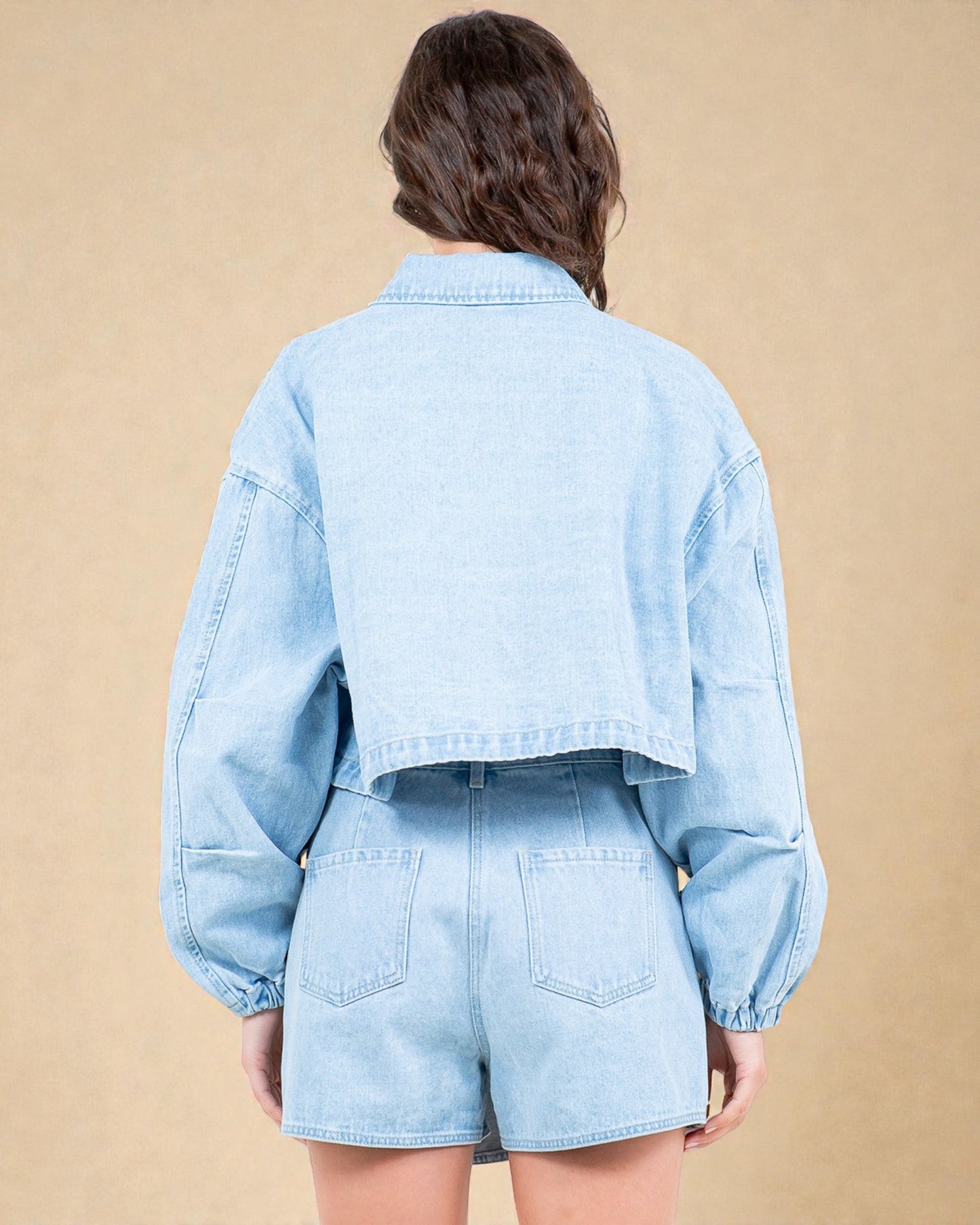 Light blue denim jacket and shorts worn by a person on a beige background
