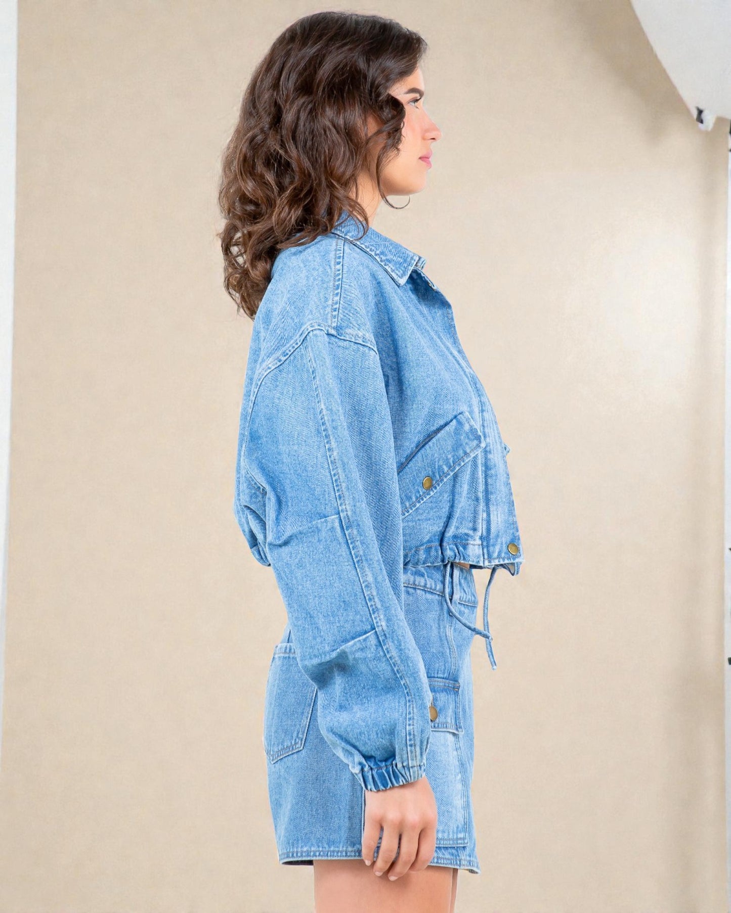 Woman wearing a denim dress against a beige background