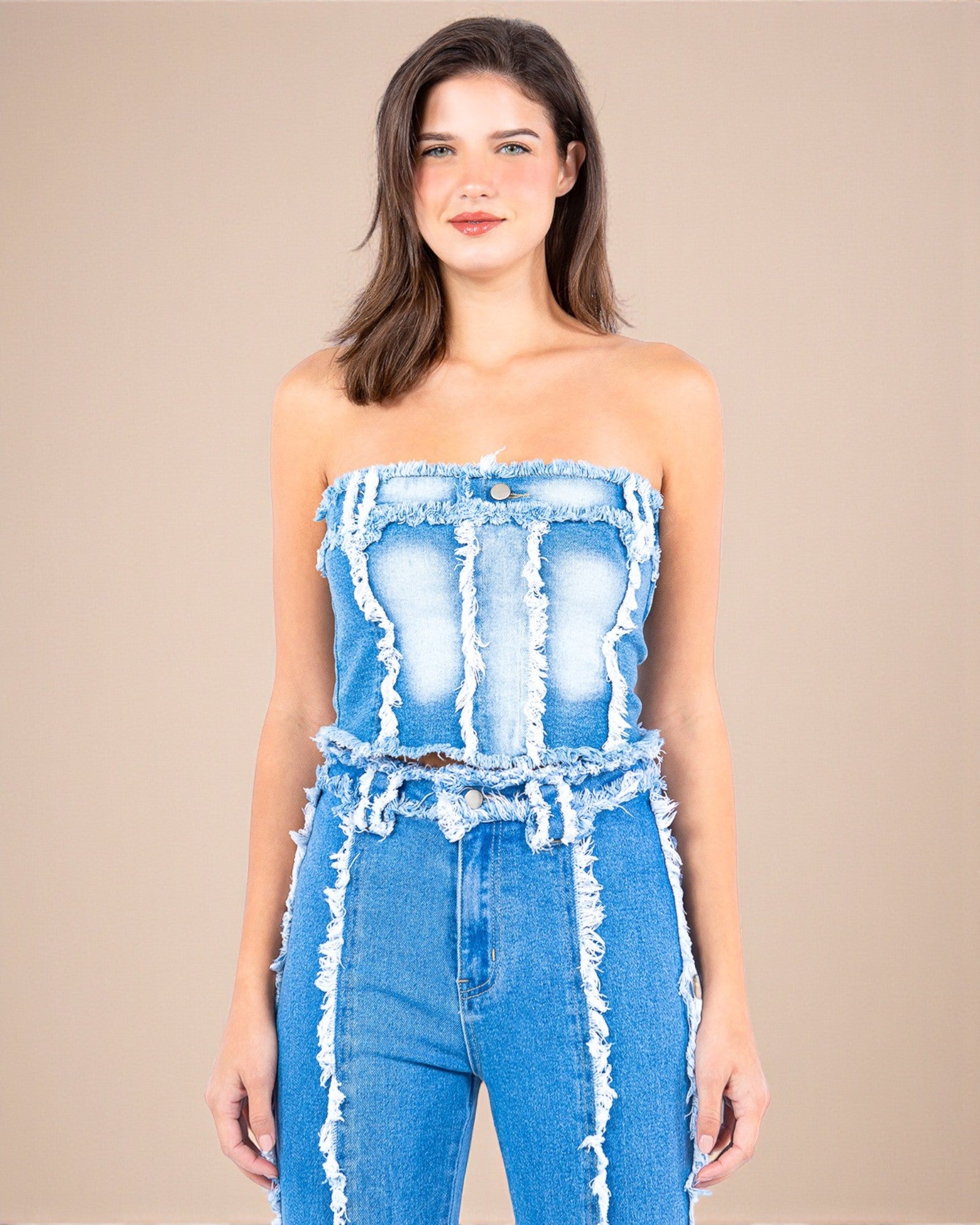 Woman wearing a denim strapless top and pants on a beige background