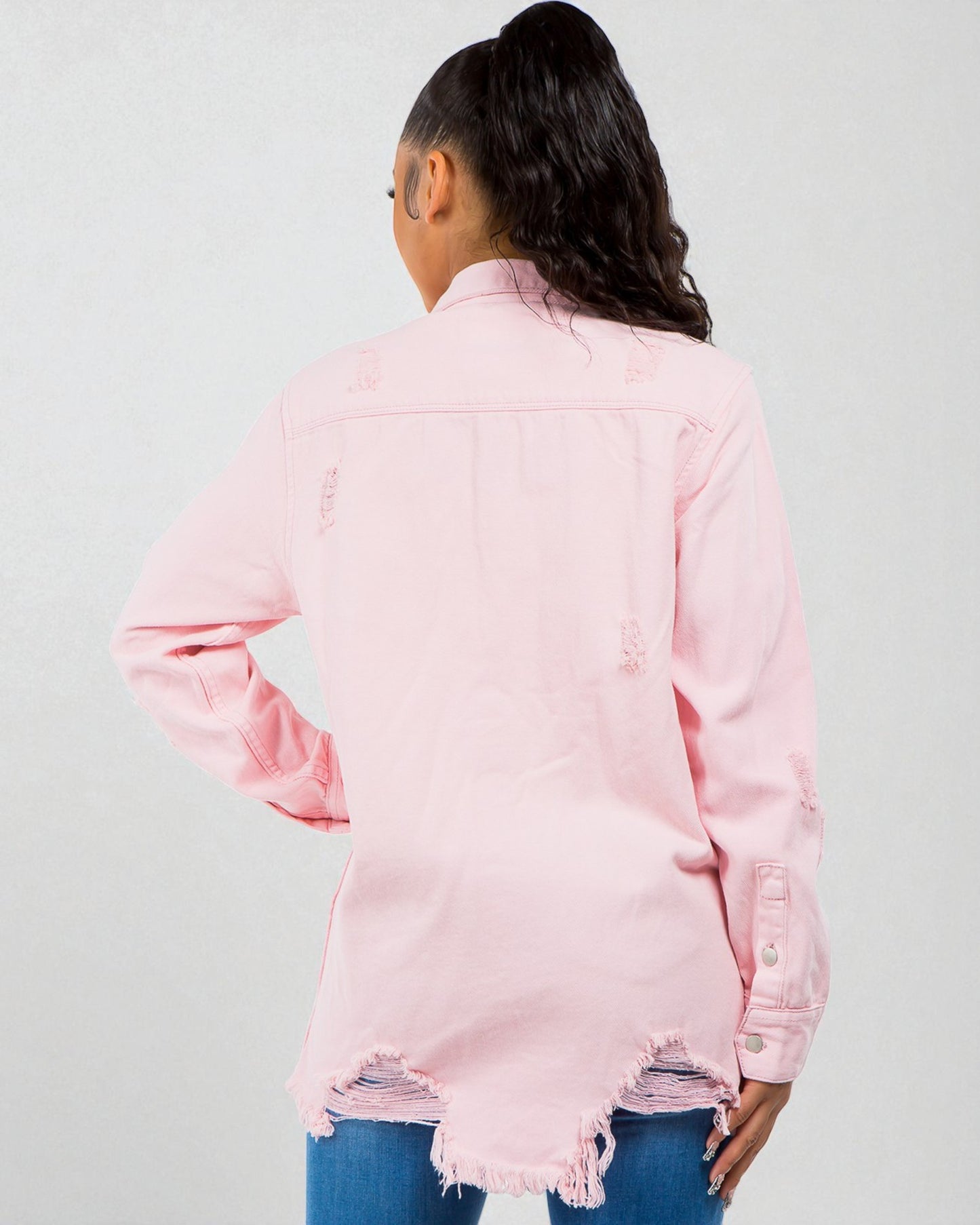 Person wearing a pink distressed denim jacket on a white background