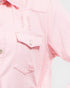 Close-up of a pink denim shirt with brand logo on pocket and chest.