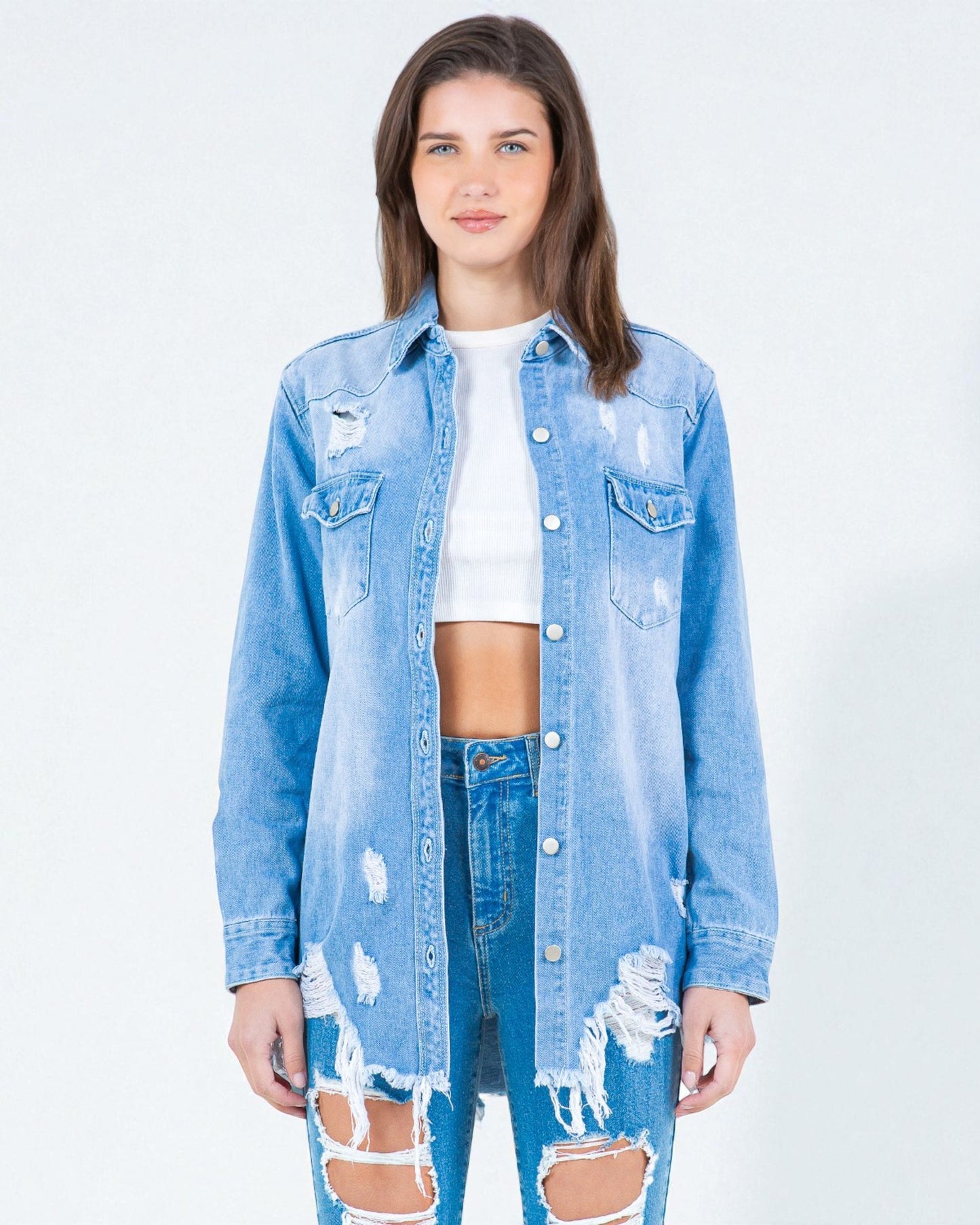 Woman wearing a distressed denim jacket and jeans on a white background