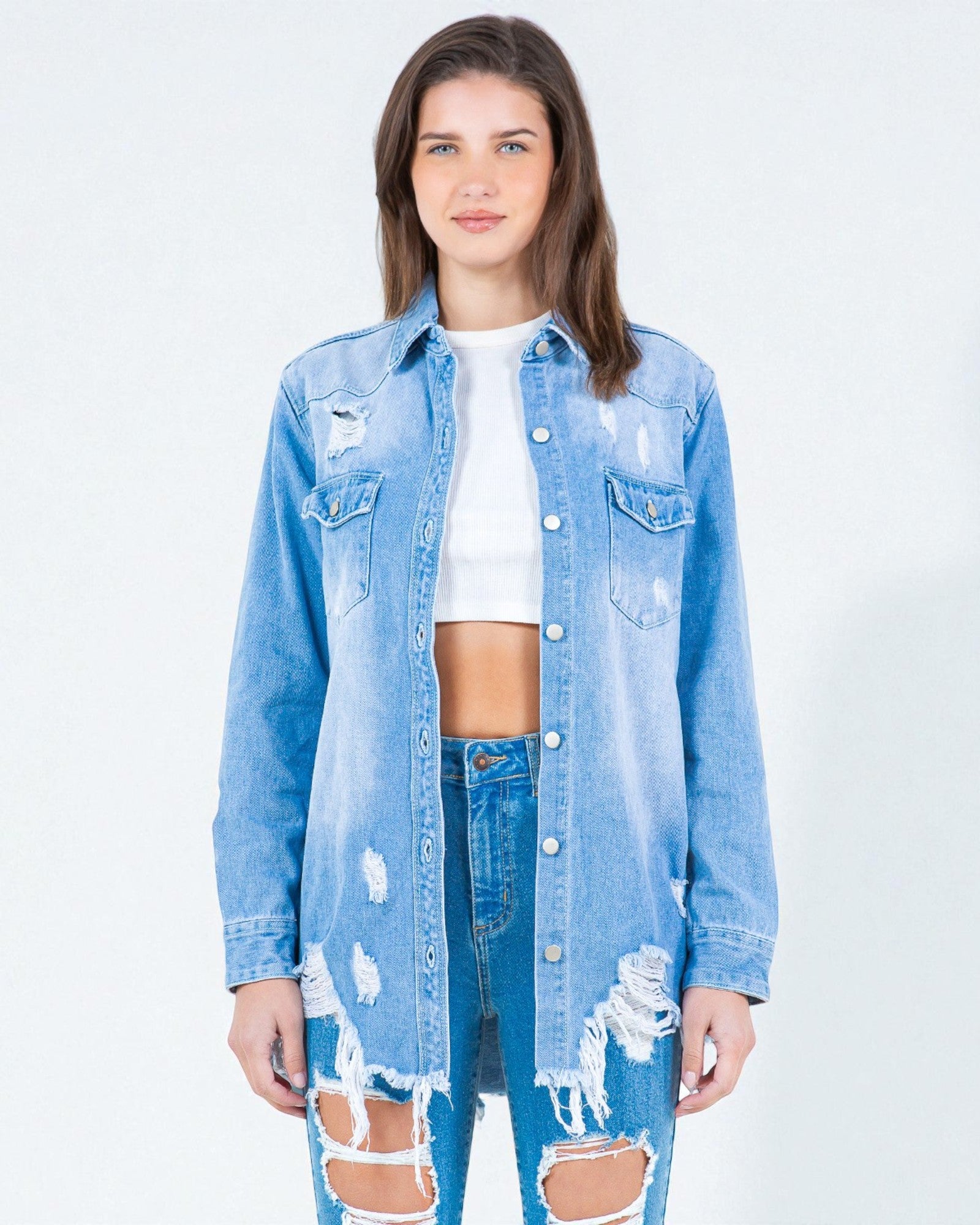 Woman wearing a distressed denim jacket and jeans on a white background