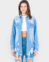 Woman wearing a distressed denim jacket and jeans on a plain background