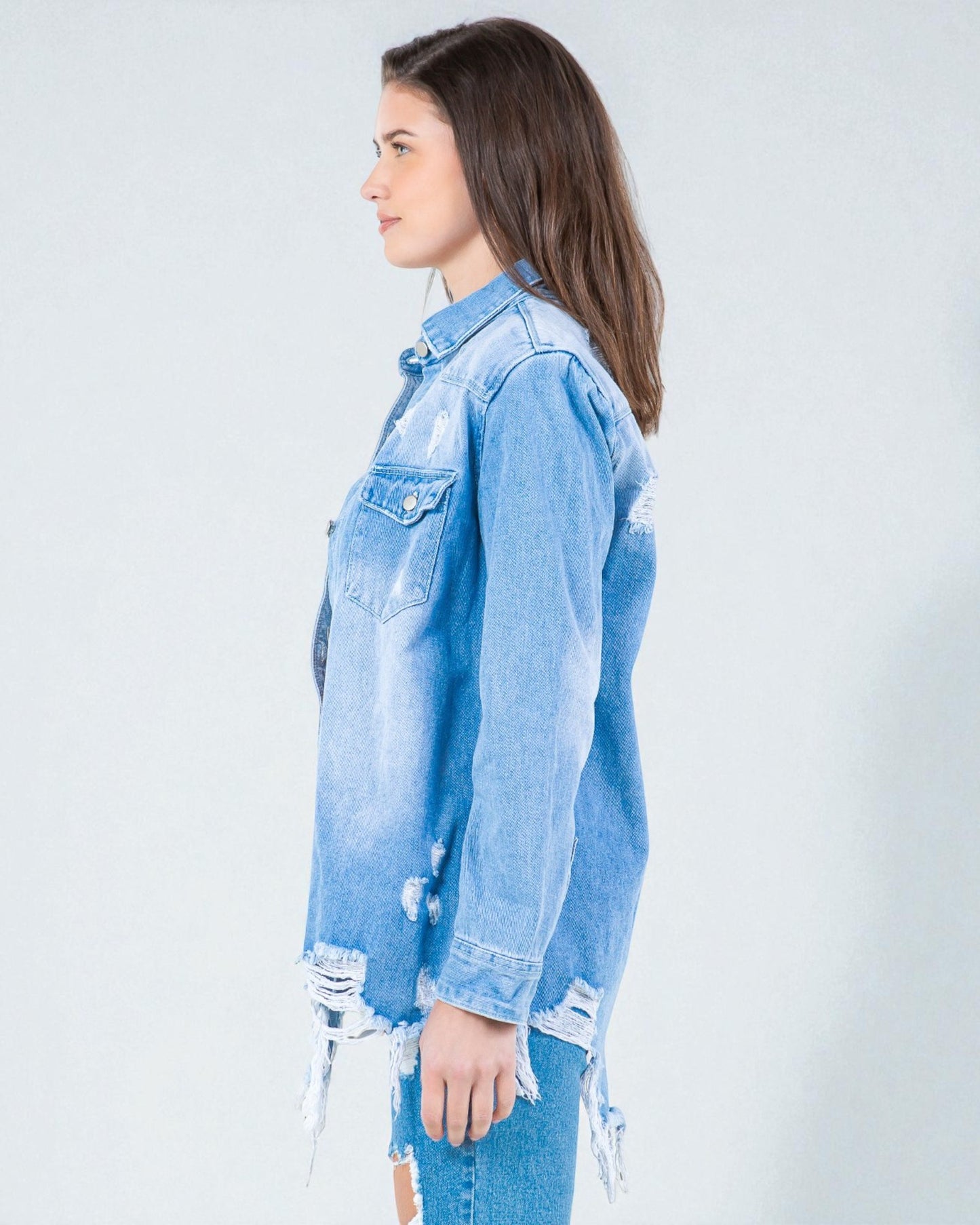 Woman wearing a light blue denim jacket with distressed details on a white background