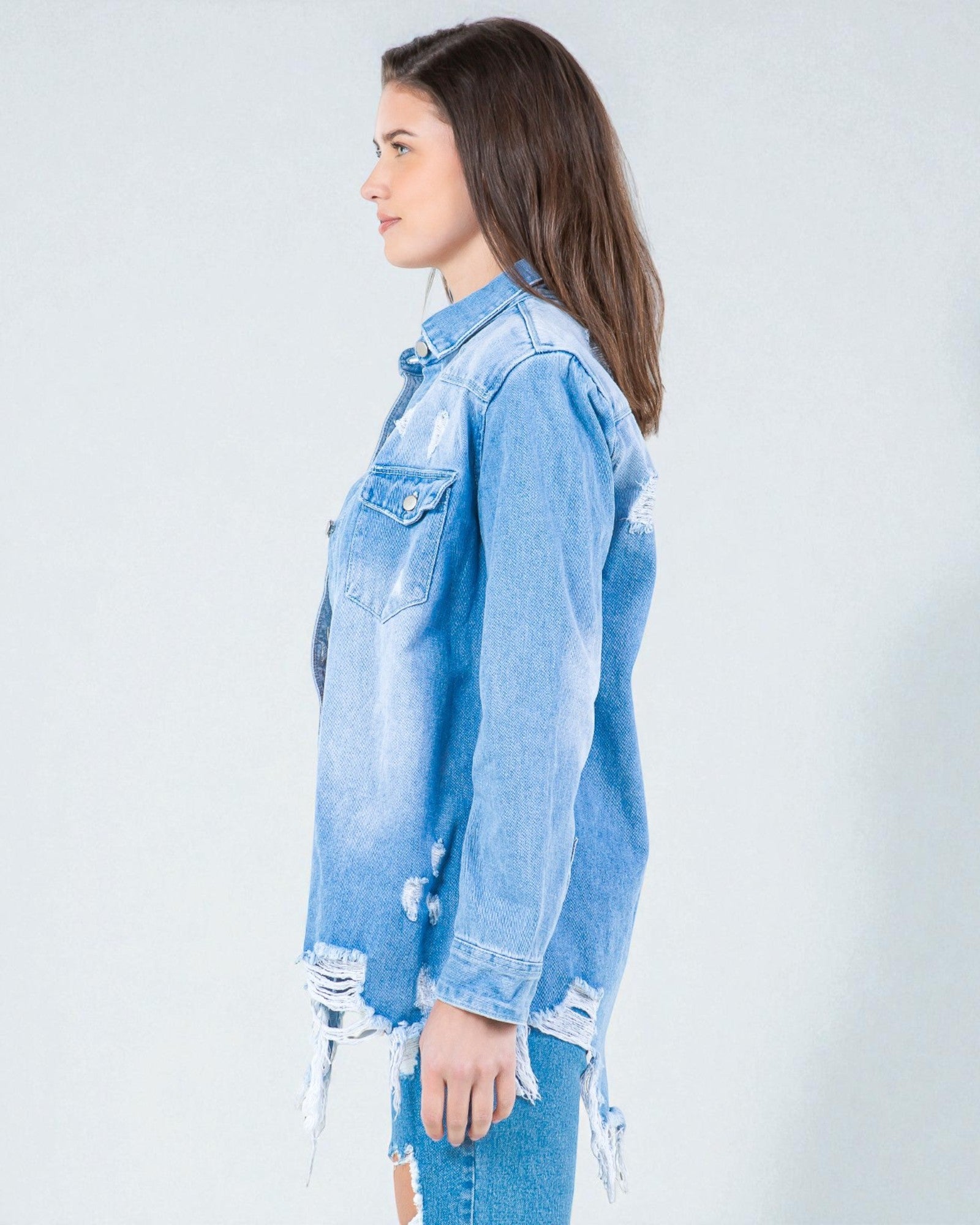 Woman wearing a light blue denim jacket with distressed details on a white background