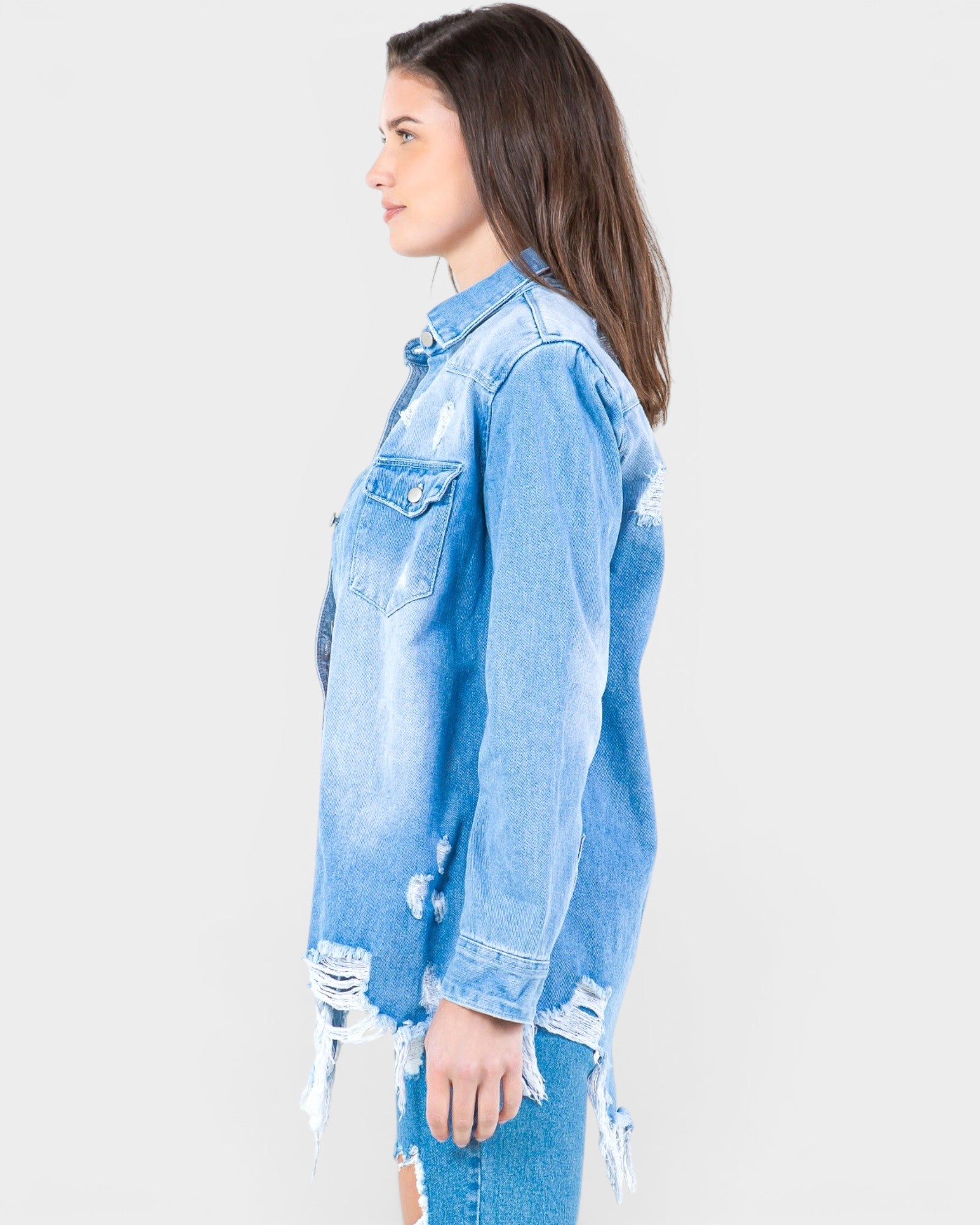 Woman wearing a light blue distressed denim jacket on a white background
