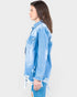 Woman wearing a light blue distressed denim jacket on a white background