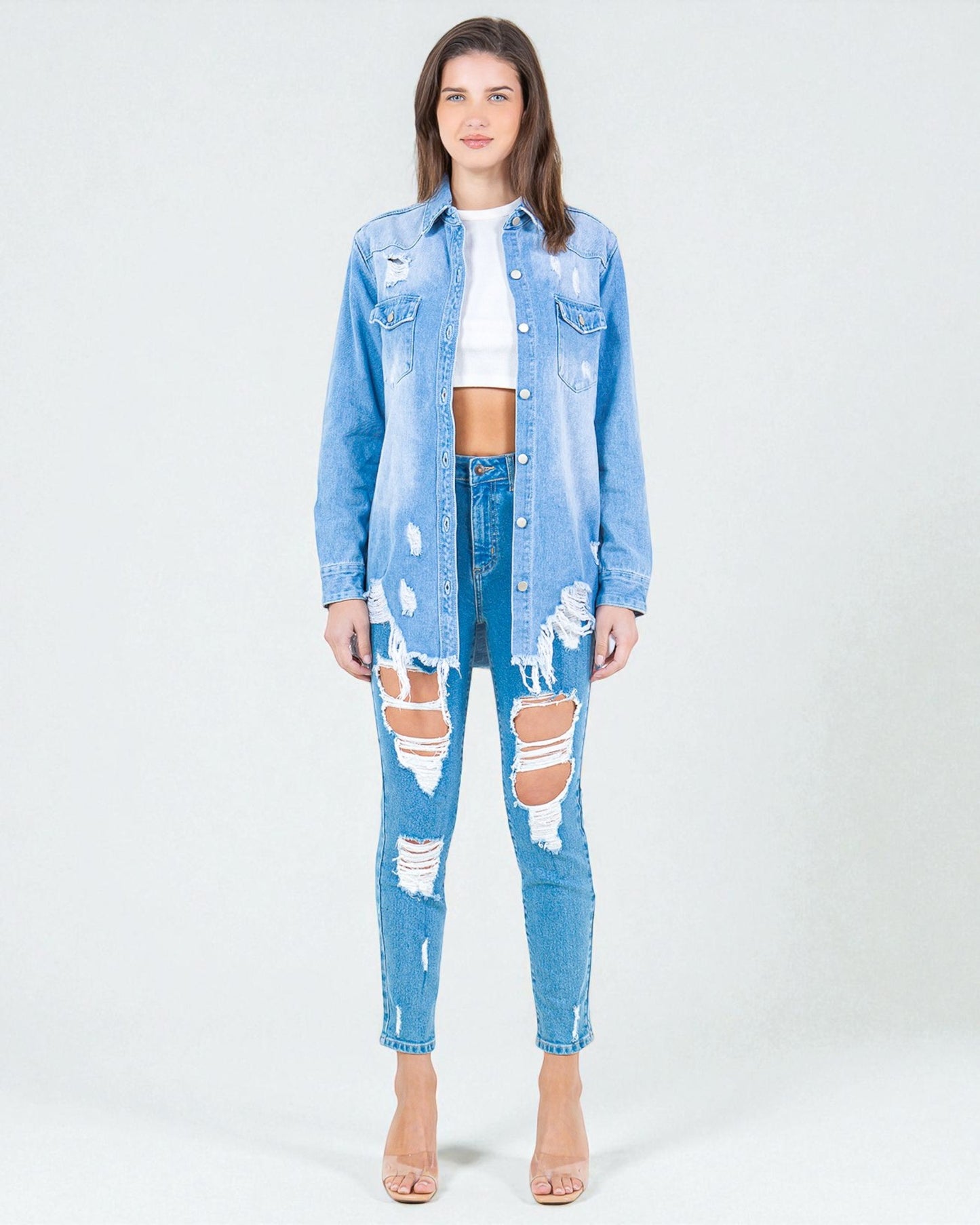 Woman wearing a light blue denim jacket and jeans on a white background