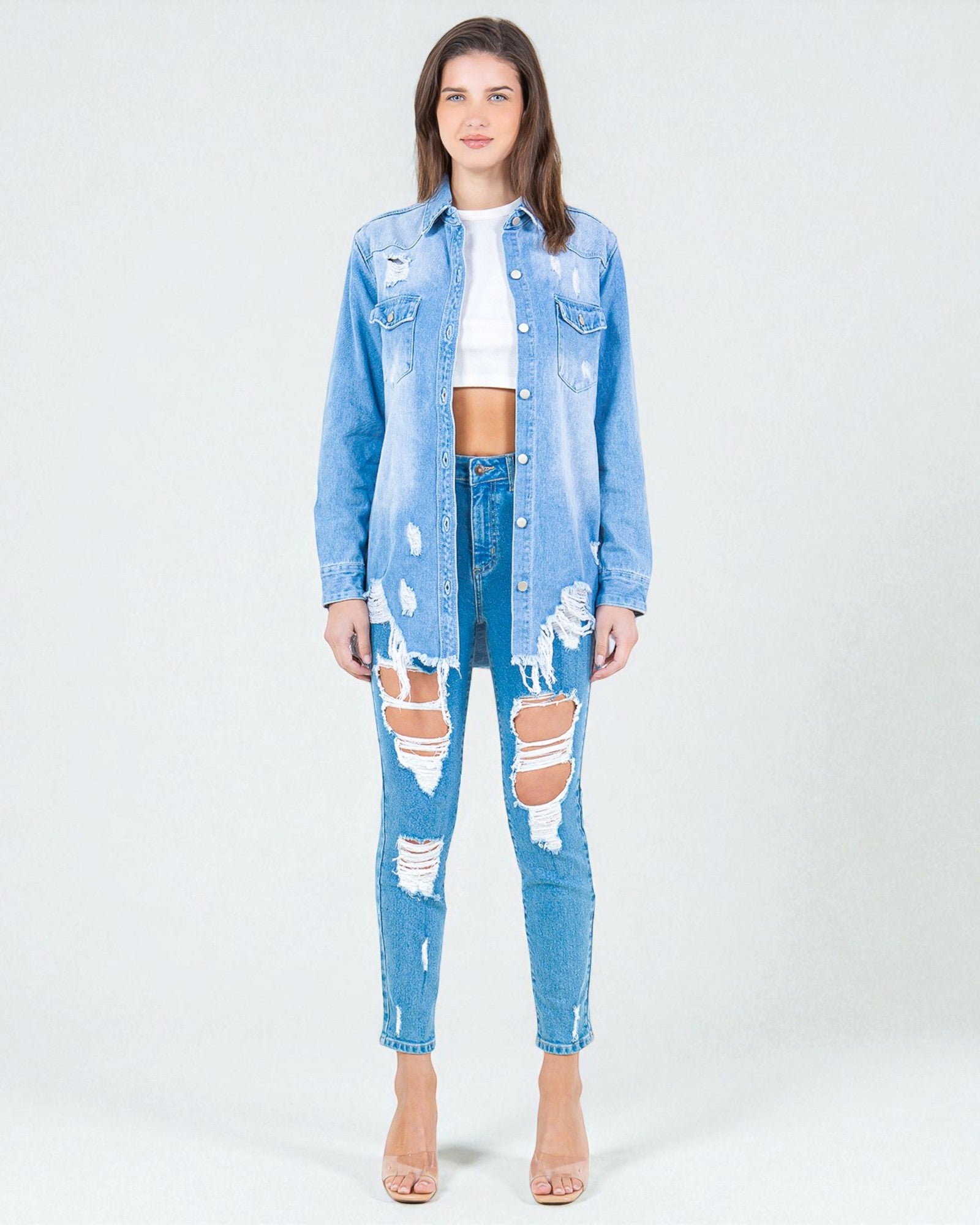 Woman wearing a light blue denim jacket and jeans on a white background
