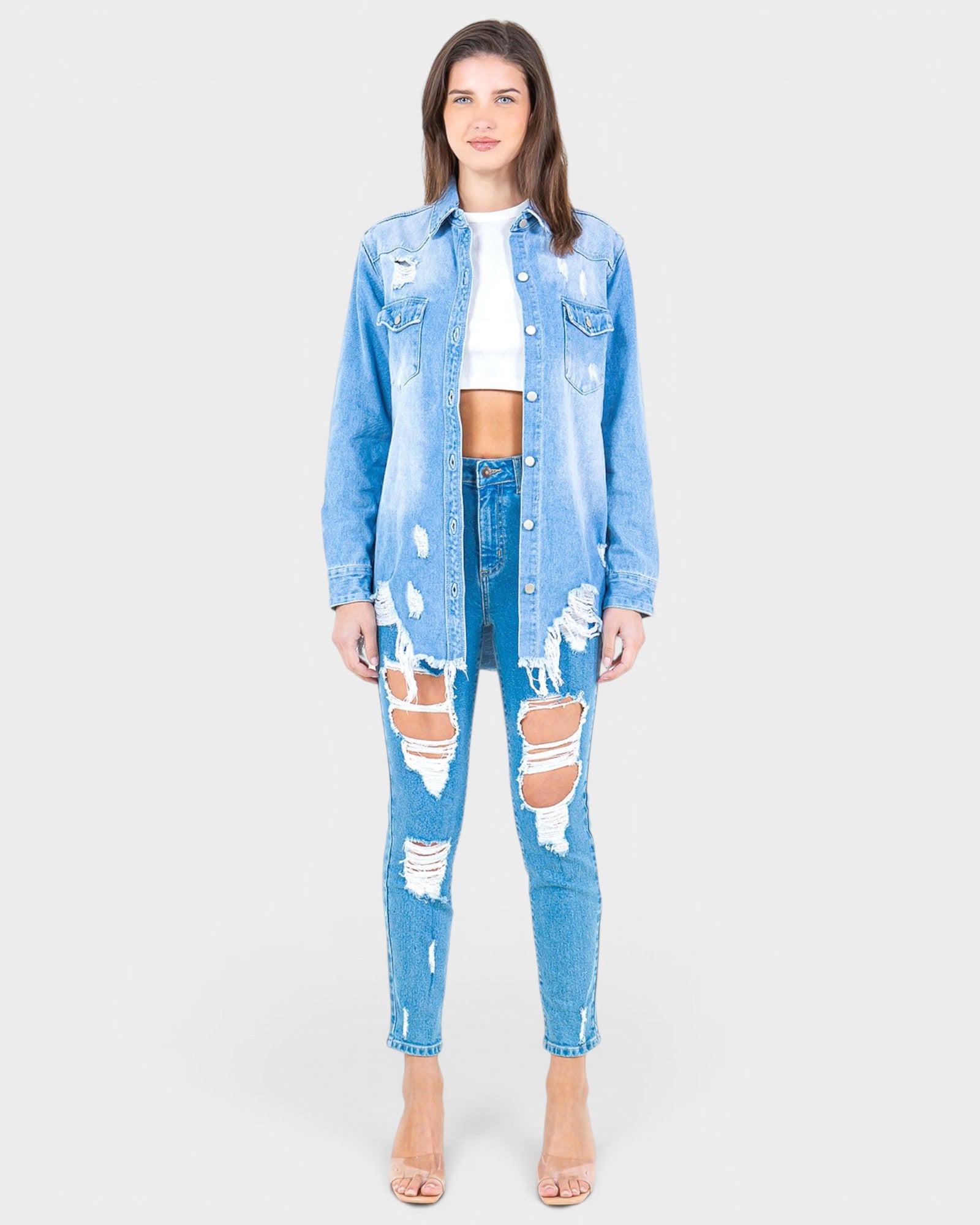 Woman wearing a distressed denim outfit on a white background