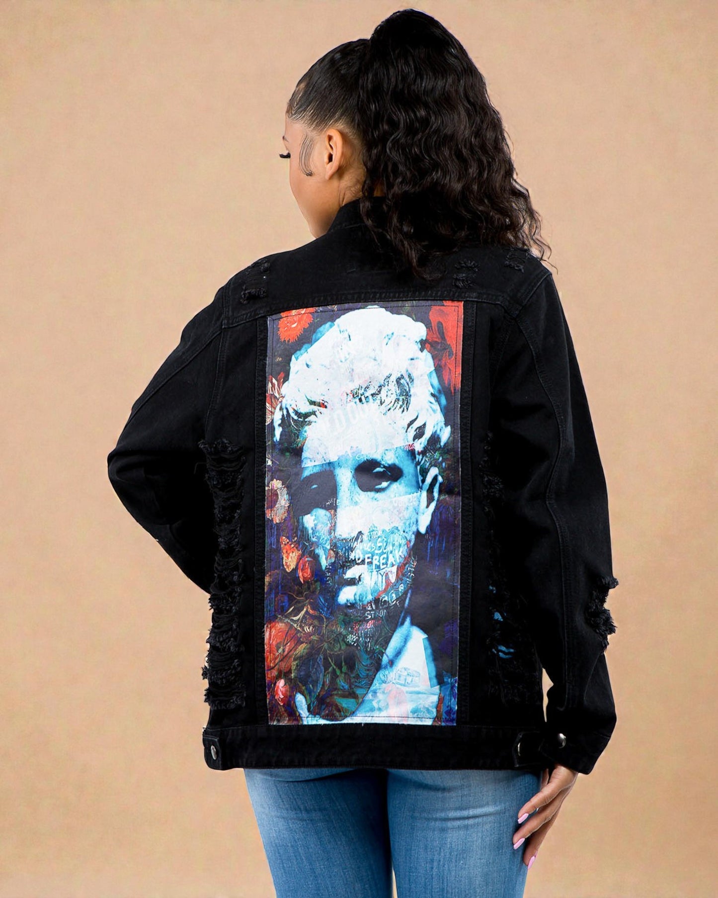 Person wearing a black jacket with a colorful graphic on the back against a beige background