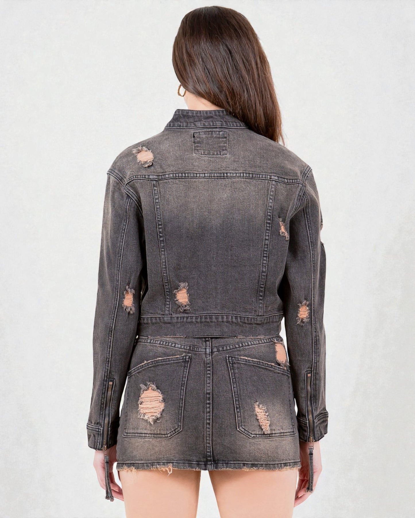 Back view of a distressed black denim jacket on a plain background