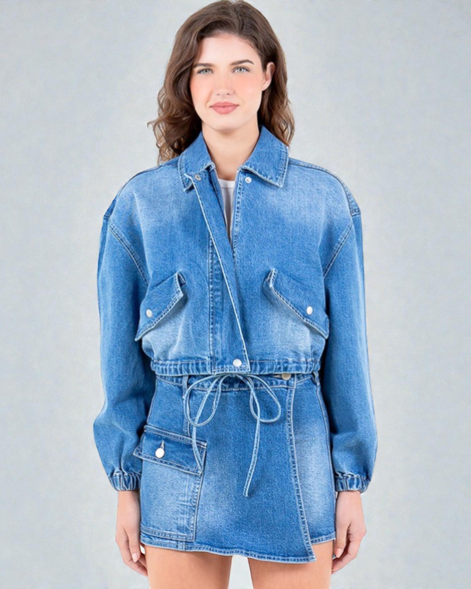 Woman wearing a blue denim jacket and skirt on a gray background