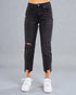 Black distressed jeans worn by a person on a gray background