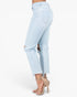 Light wash blue cropped jeans with side cutouts, shown on a model from the back wearing beige high-heeled sandals against a white studio background.