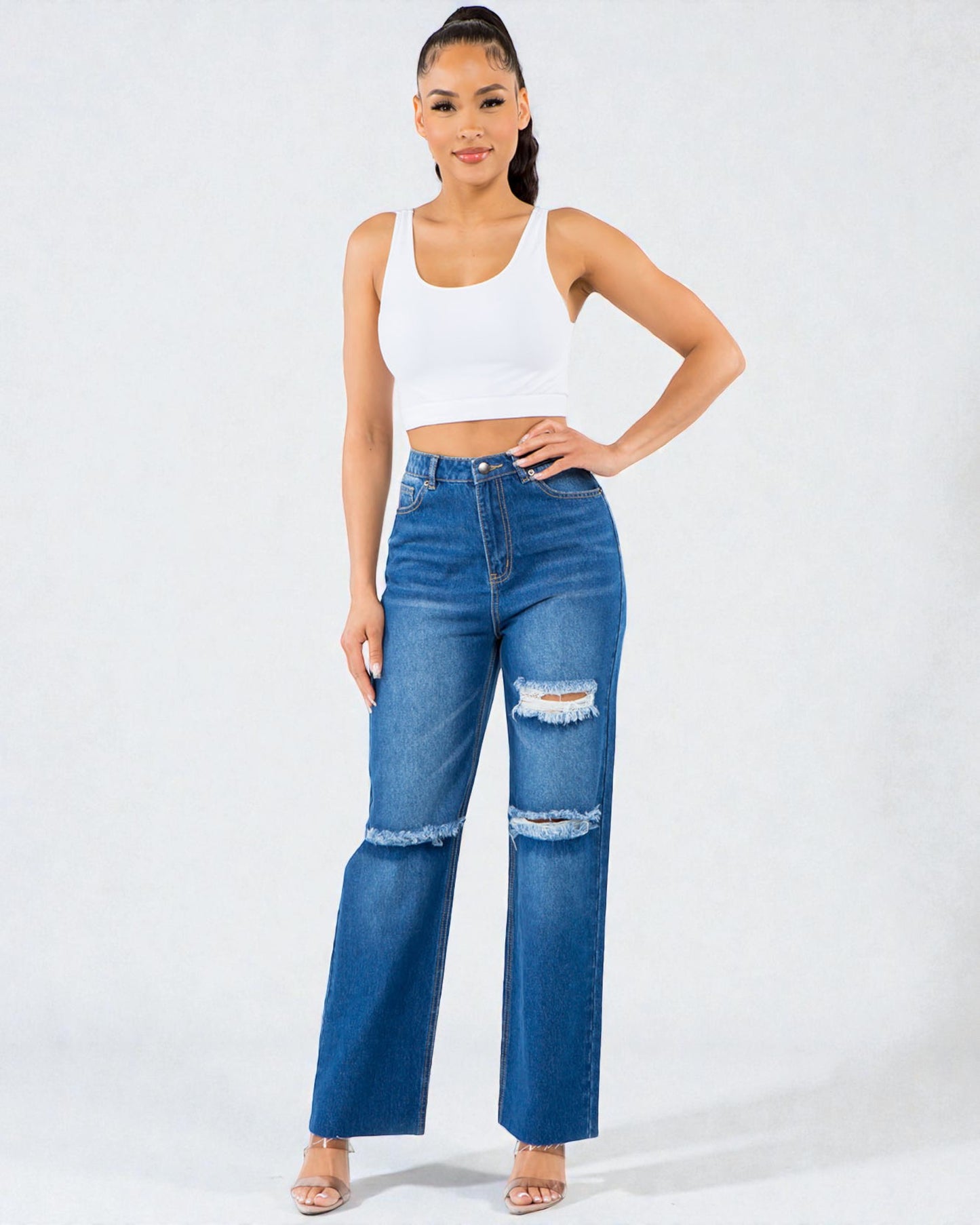 Woman wearing a white tank top and blue jeans on a white background