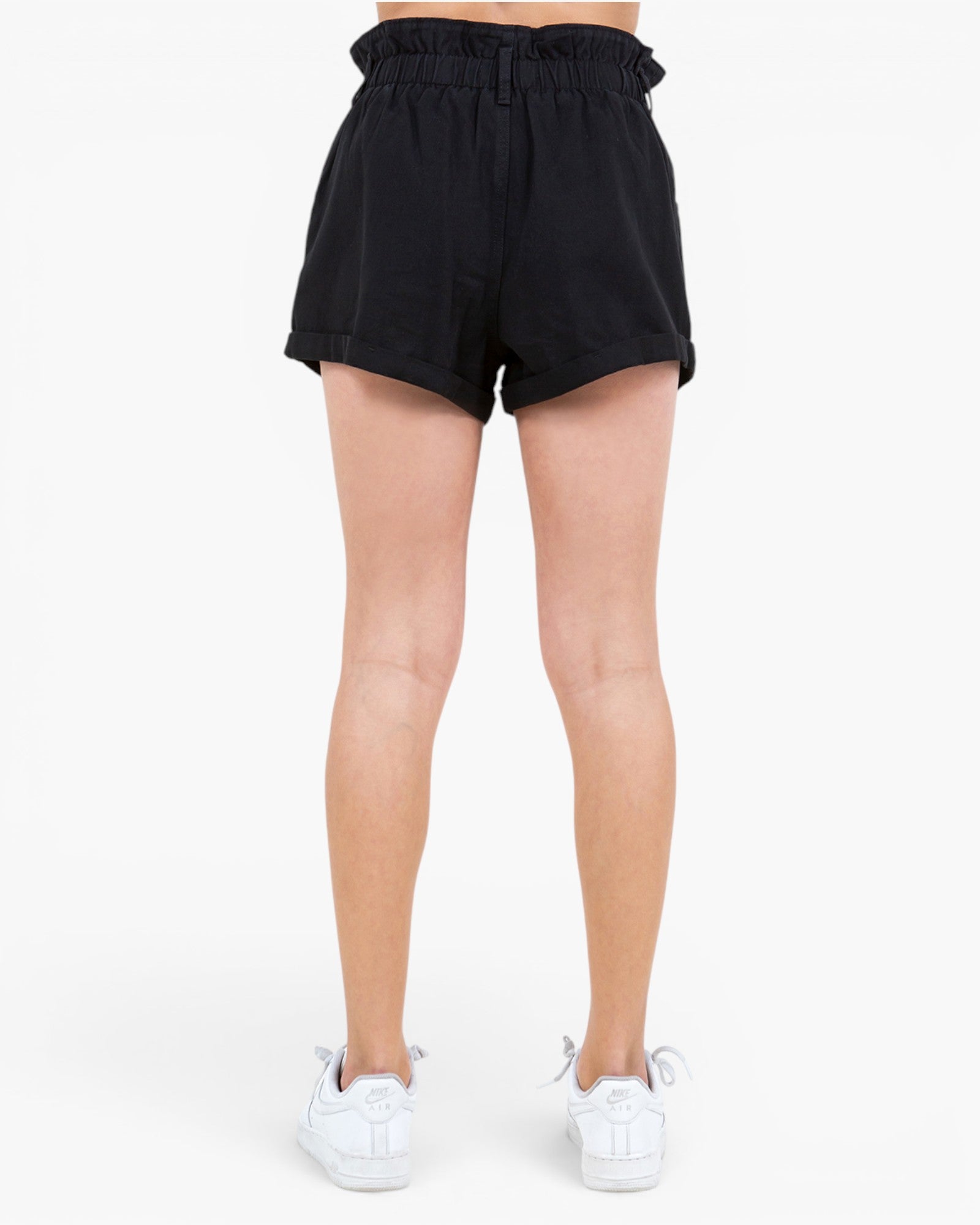 Black high-waisted shorts with a ruffled elastic waistband, shown on a model from the back against a plain white background.