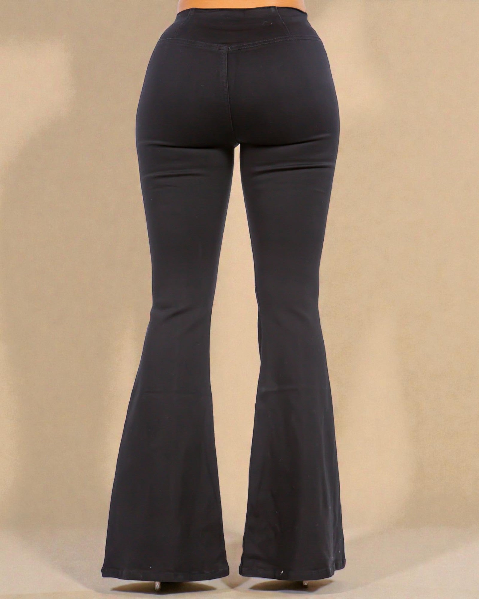 Black bell-bottom pants on a beige background