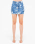 A model's lower body wearing a blue and white distressed denim cargo mini skirt with frayed hems, paired with clear high-heeled sandals, against a plain white background.