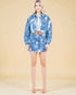 Woman wearing a blue tie-dye denim jacket and skirt set on a beige background