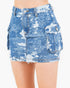 A close-up of a model wearing a light blue denim mini skirt with a distressed, faded camouflage pattern, side cargo pockets, and a frayed hem.