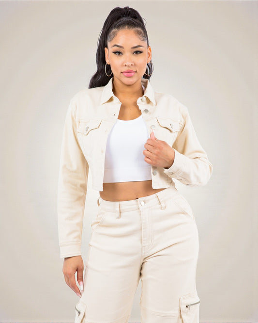 Woman wearing a beige jacket and pants with a white top against a plain background