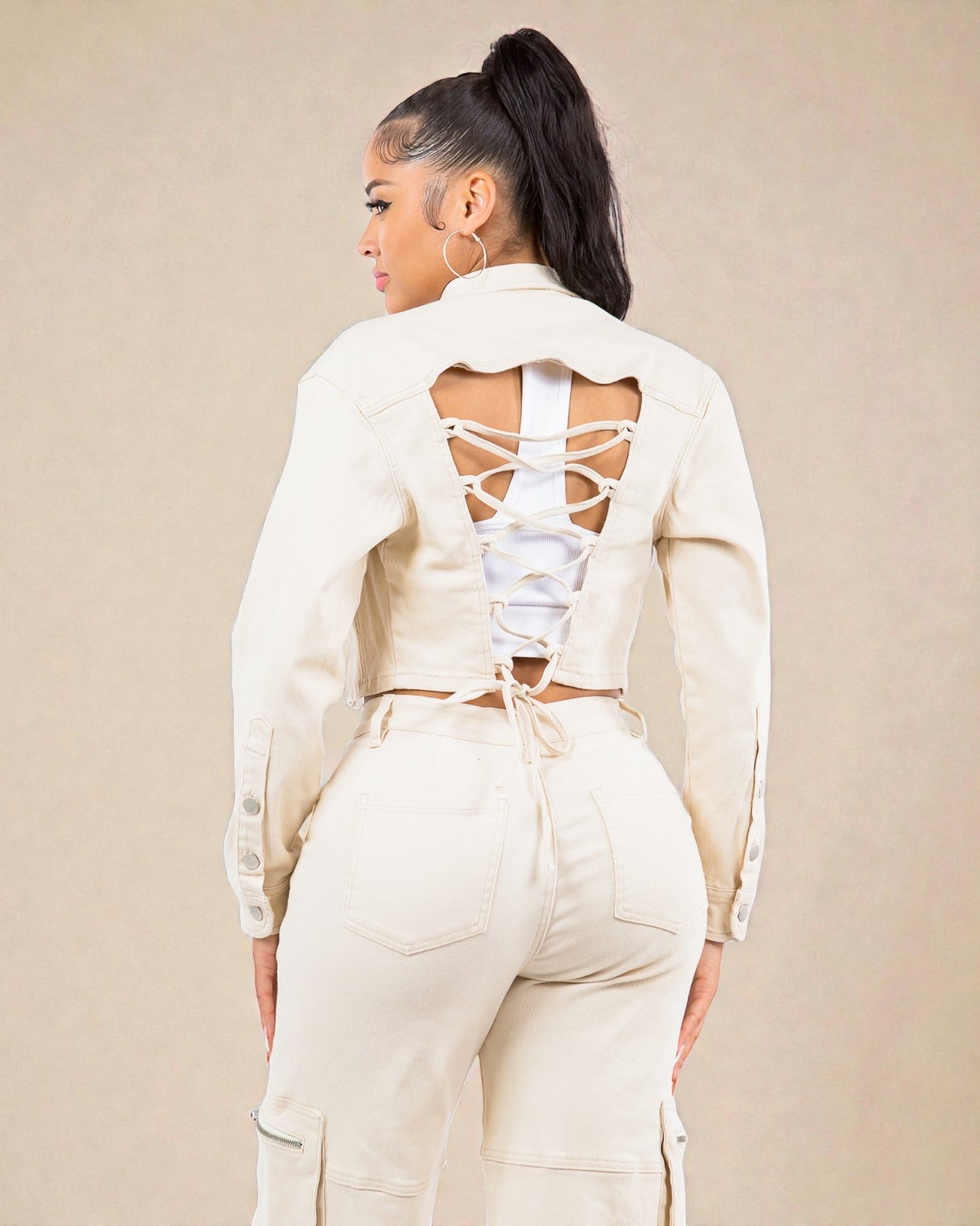 Person wearing a cream-colored outfit with a backless top and matching pants on a beige background
