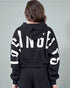 Person wearing a black hoodie with large white text on a gray background