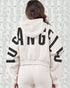 Person wearing a white hoodie with 'Los Angeles' printed on the back against a textured white wall.
