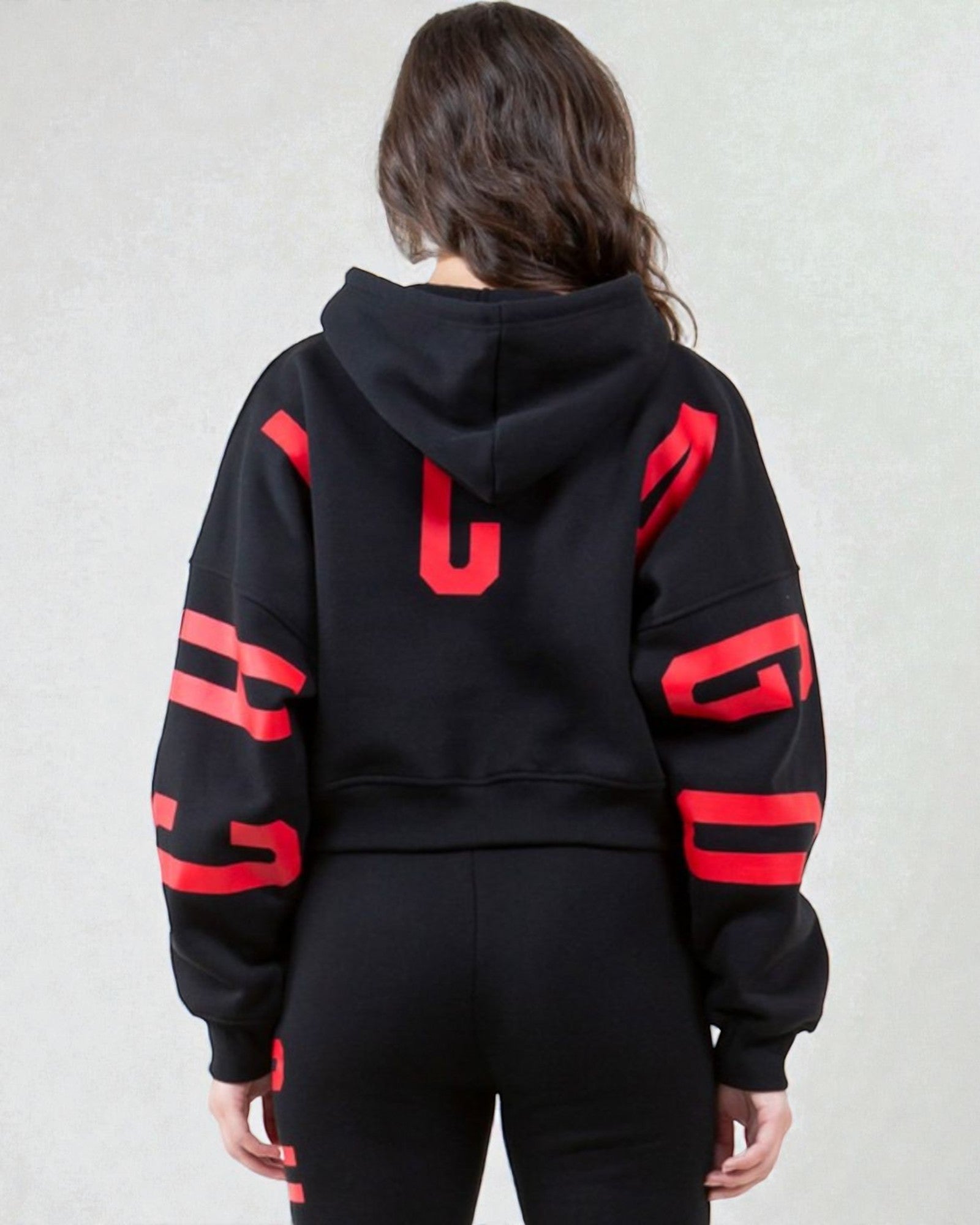 Person wearing a black hoodie with red accents on a plain background