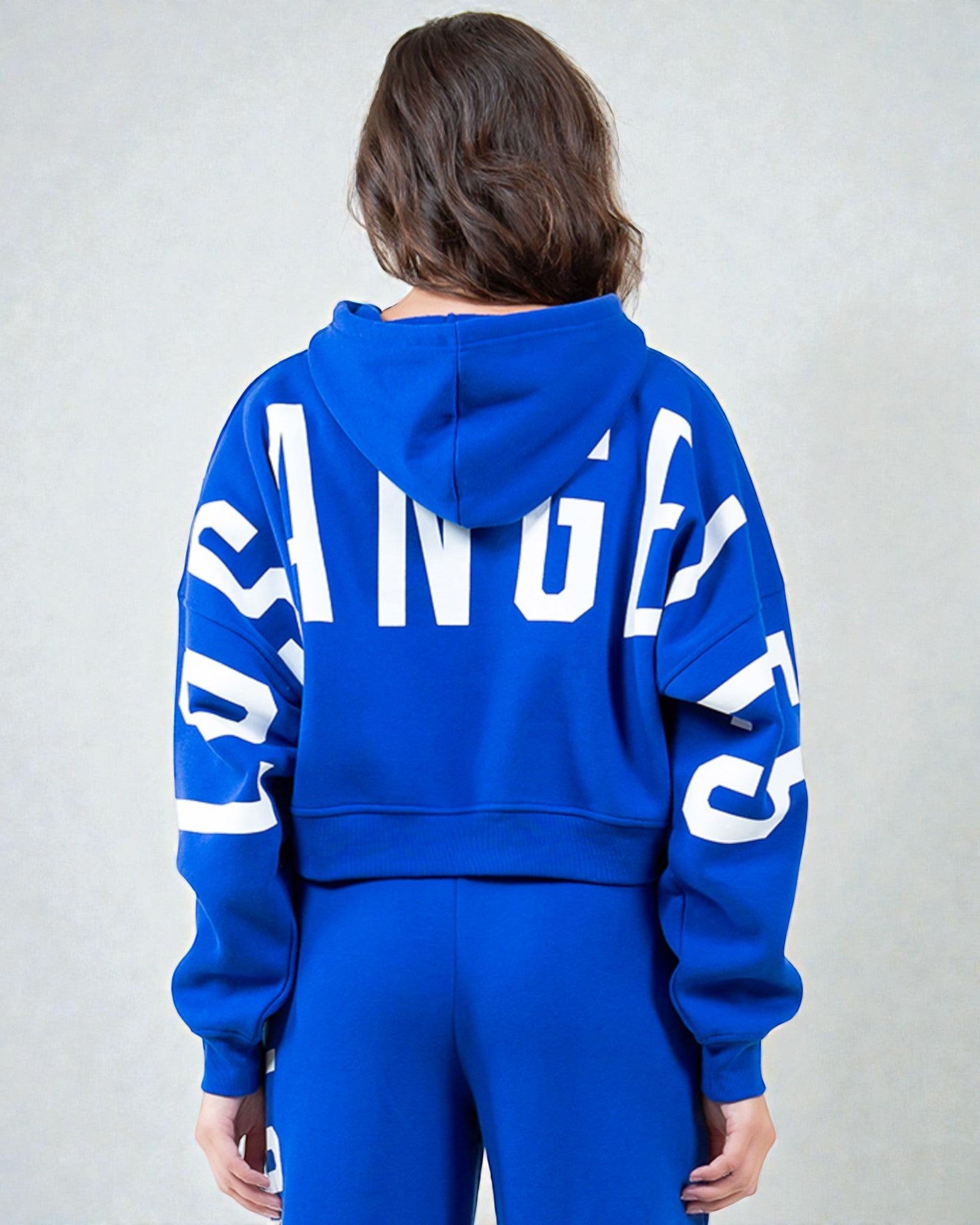 Person wearing a blue hoodie with 'ANGELS' printed on the back against a gray background