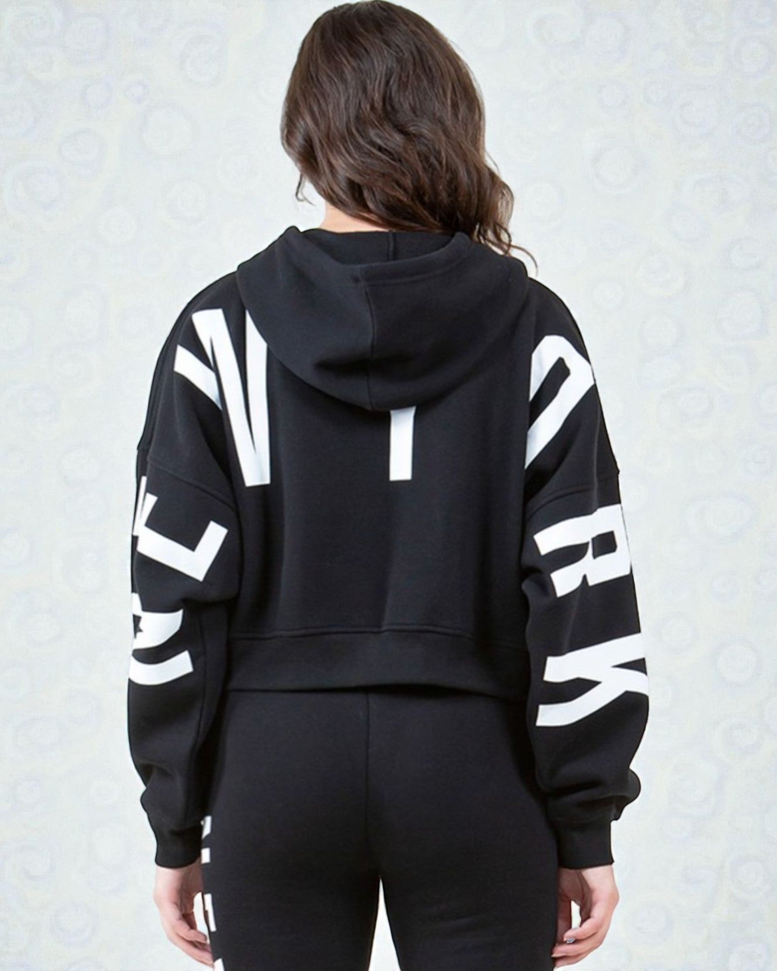 Person wearing a black hoodie with white text on the back against a light gray background