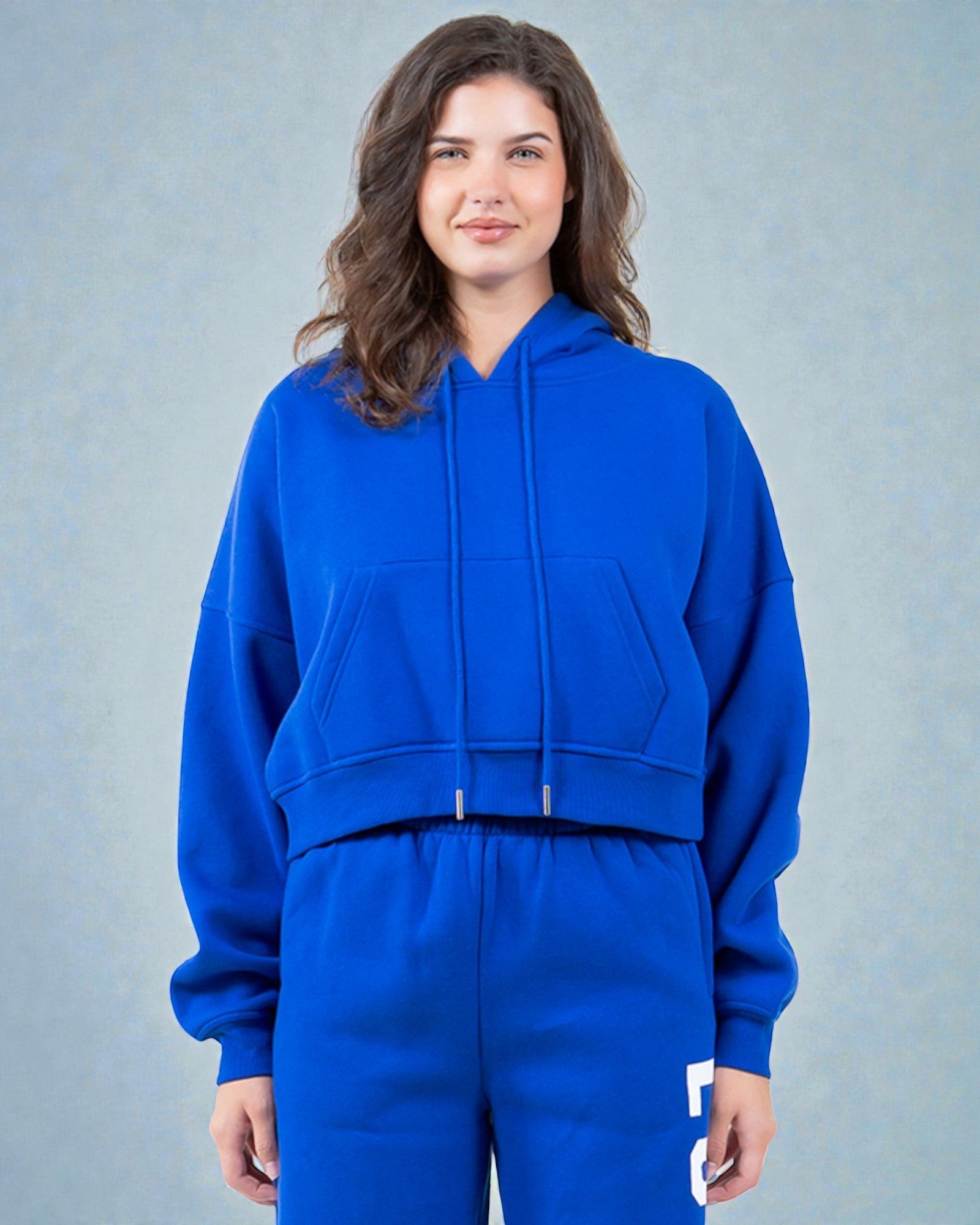 Person wearing a blue hoodie and matching pants against a gray background