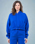 Person wearing a blue hoodie and matching pants against a gray background
