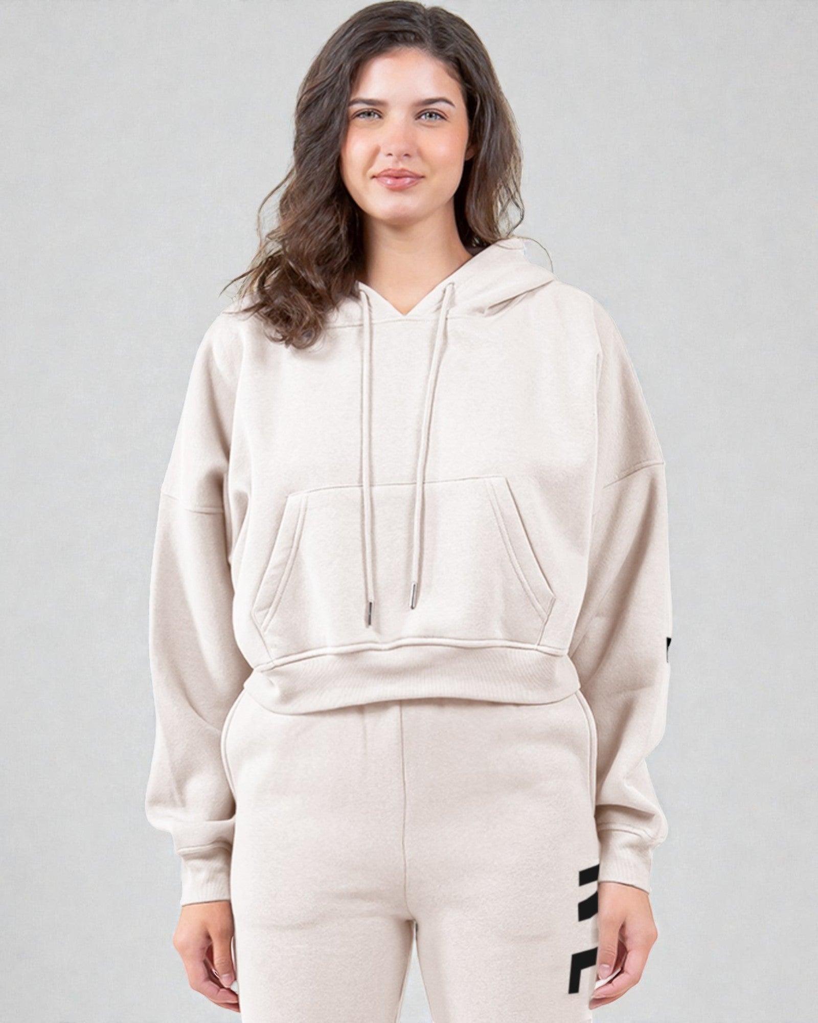 Woman wearing a beige hoodie and pants on a gray background