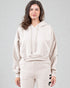 Woman wearing a beige hoodie and pants on a gray background